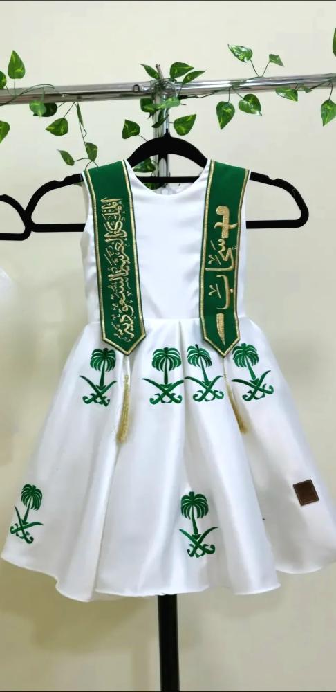 فستان أبيض وطني مطرز بشعار المملكة ووشاح أخضر