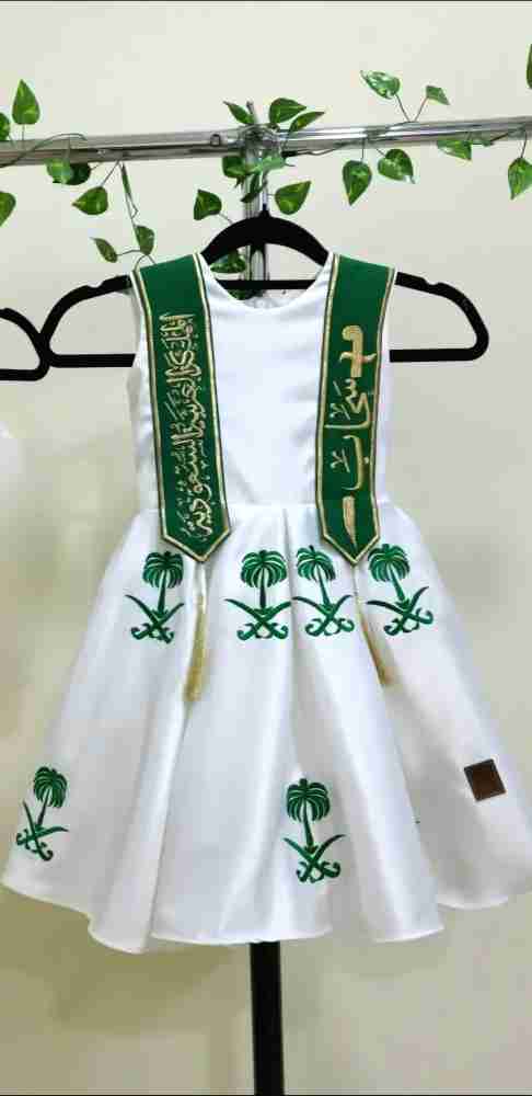 فستان أبيض وطني مطرز بشعار المملكة ووشاح أخضر